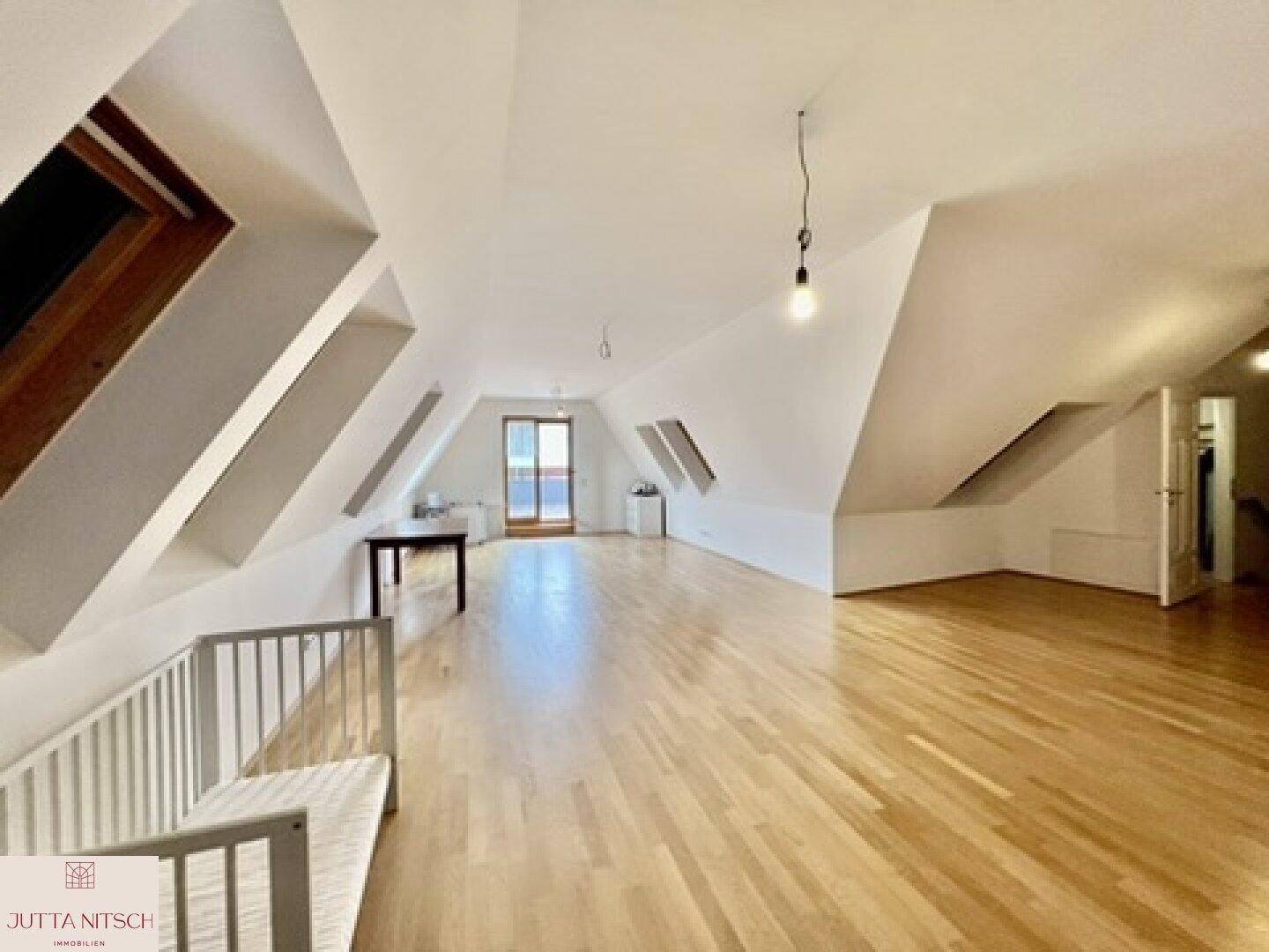 Großzügiger Dachbodenraum mit Holzparkett, Dachfenstern und viel natürlichem Licht.