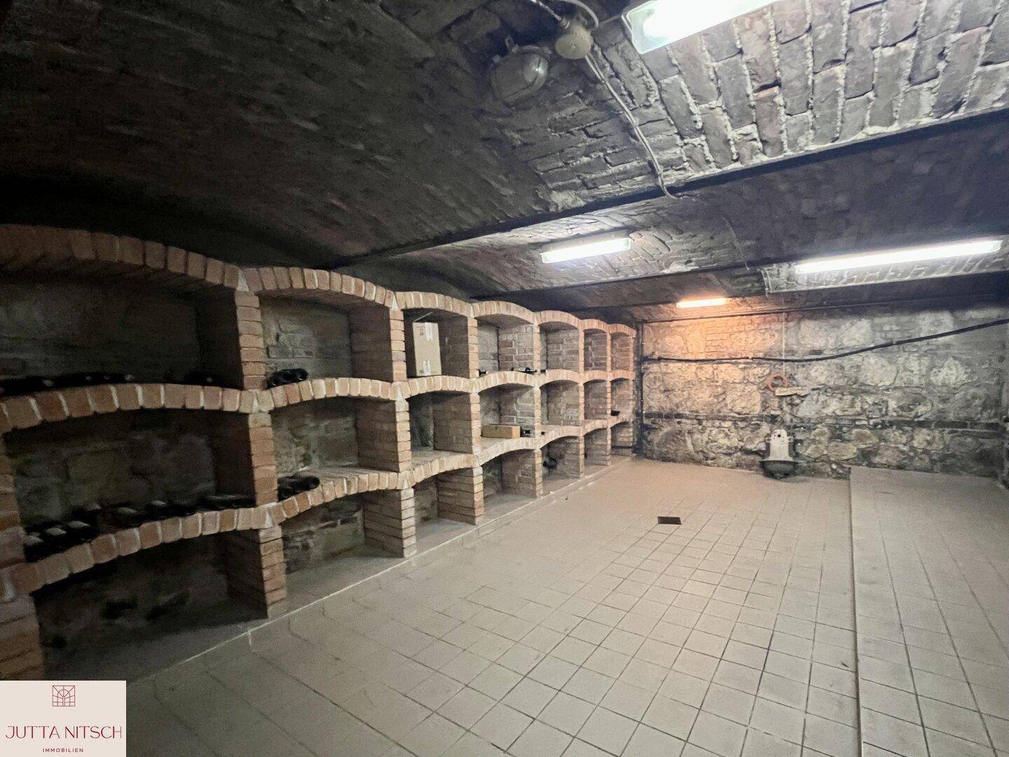 Historischer Weinkeller mit gemauerten Regalen und Gewölbedecke für die Lagerung von Flaschen.