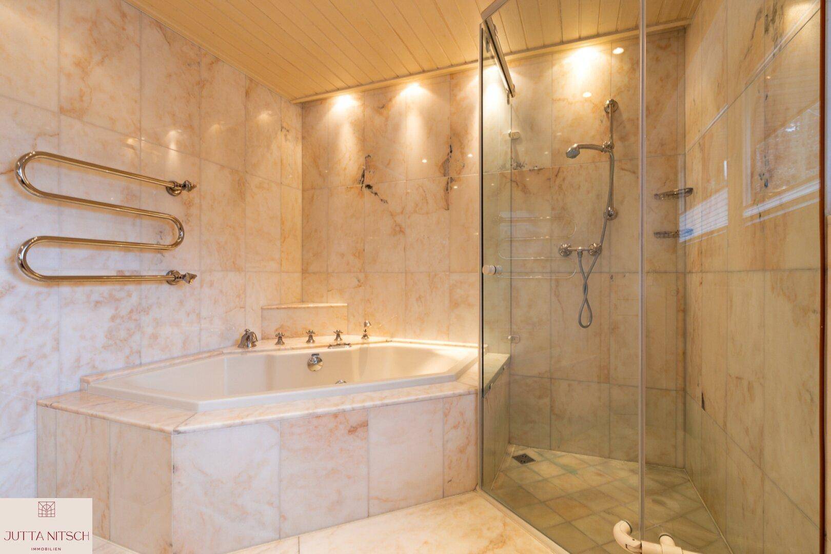 Elegantes Badezimmer mit Eckbadewanne, Duschkabine und Marmorfliesen.