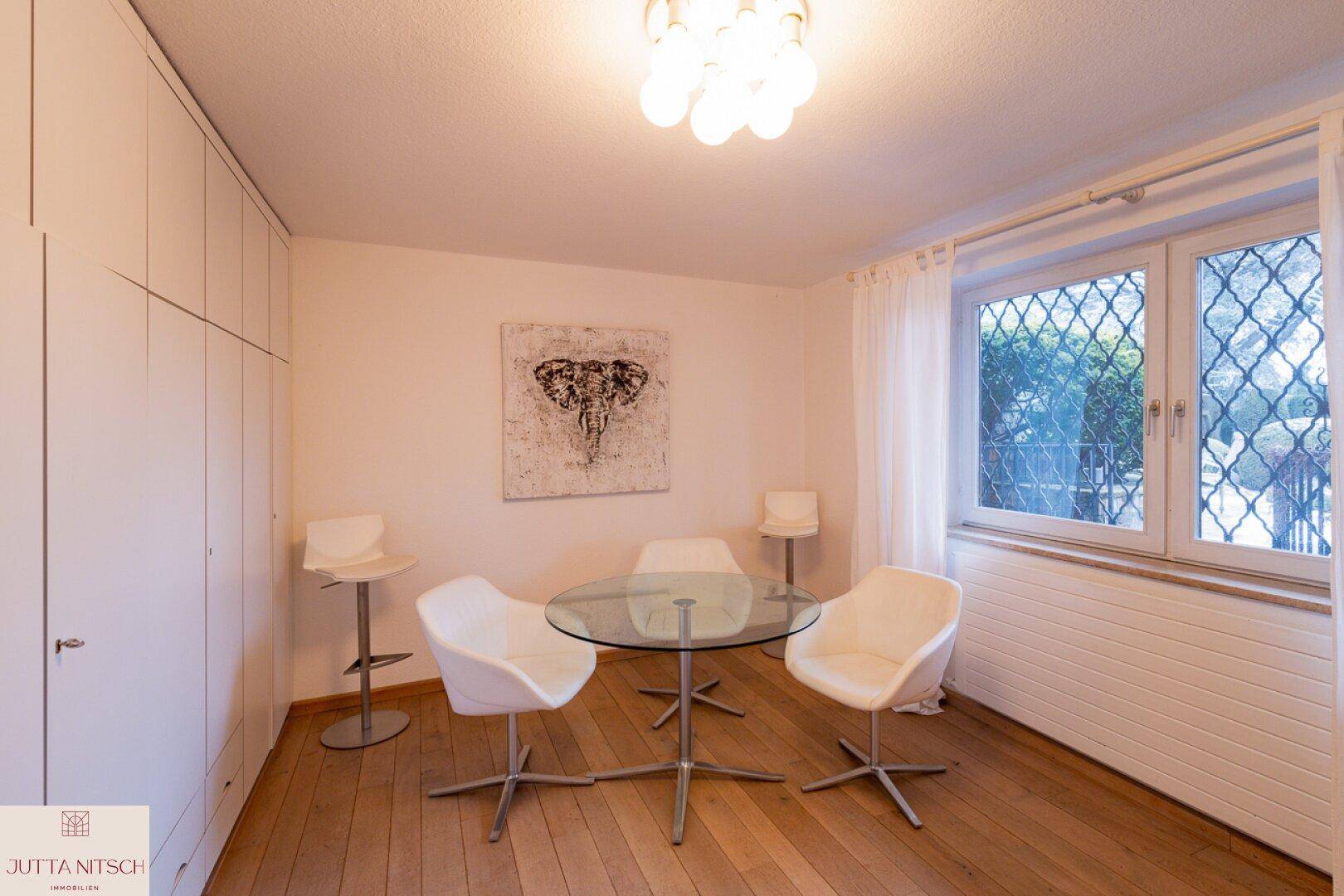 Helles Zimmer mit Holzboden, Einbauschränken und modernem Tisch mit Stühlen.