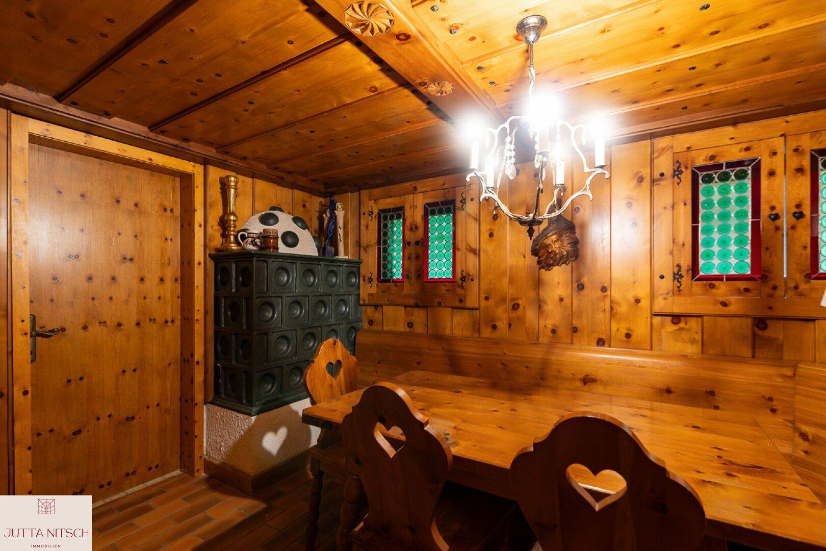 Rustikaler Essbereich mit Holztäfelung, Kachelofen und traditionellen Möbeln.