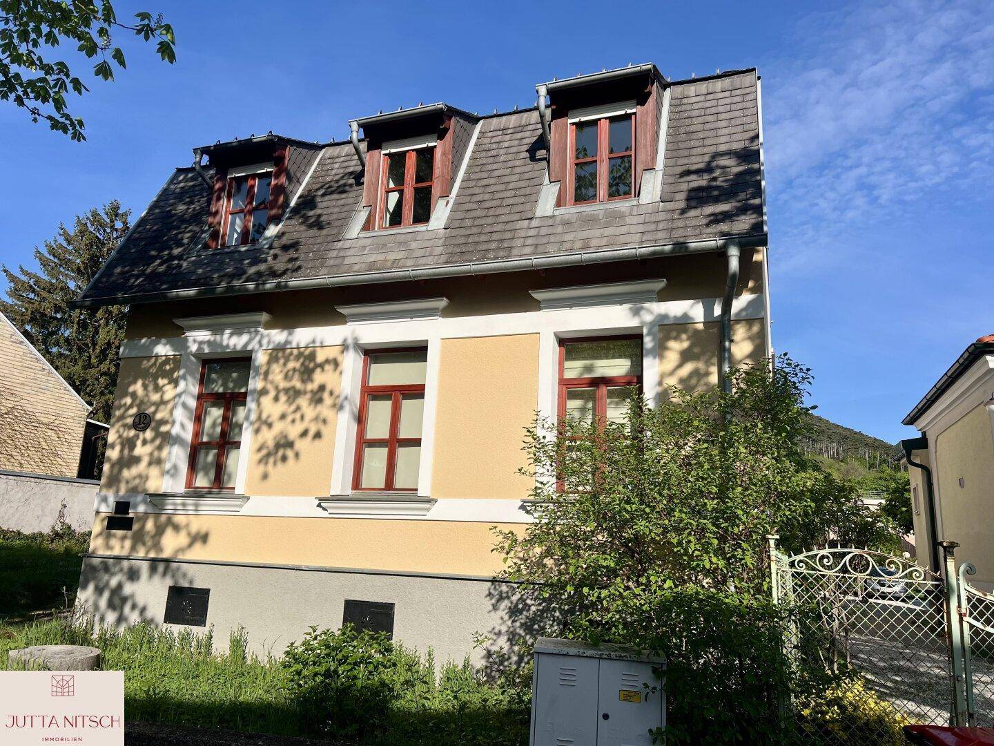 Historisches Gebäude mit gelber Fassade, Mansarddach und traditionellen Fenstern unter blauem Himmel.
