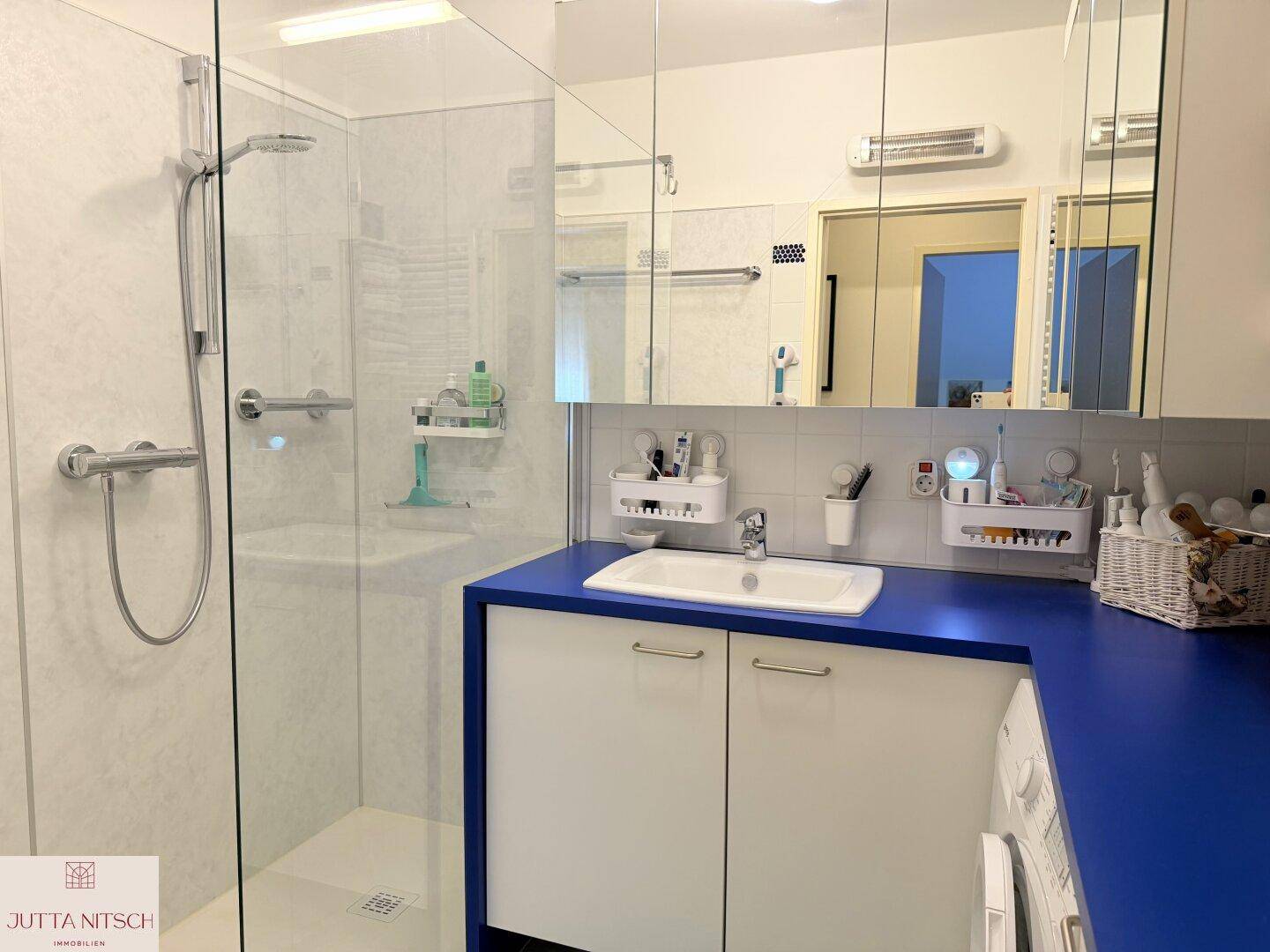 Modernes Badezimmer mit Duschkabine, Waschbecken und einer blauen Arbeitsplatte.