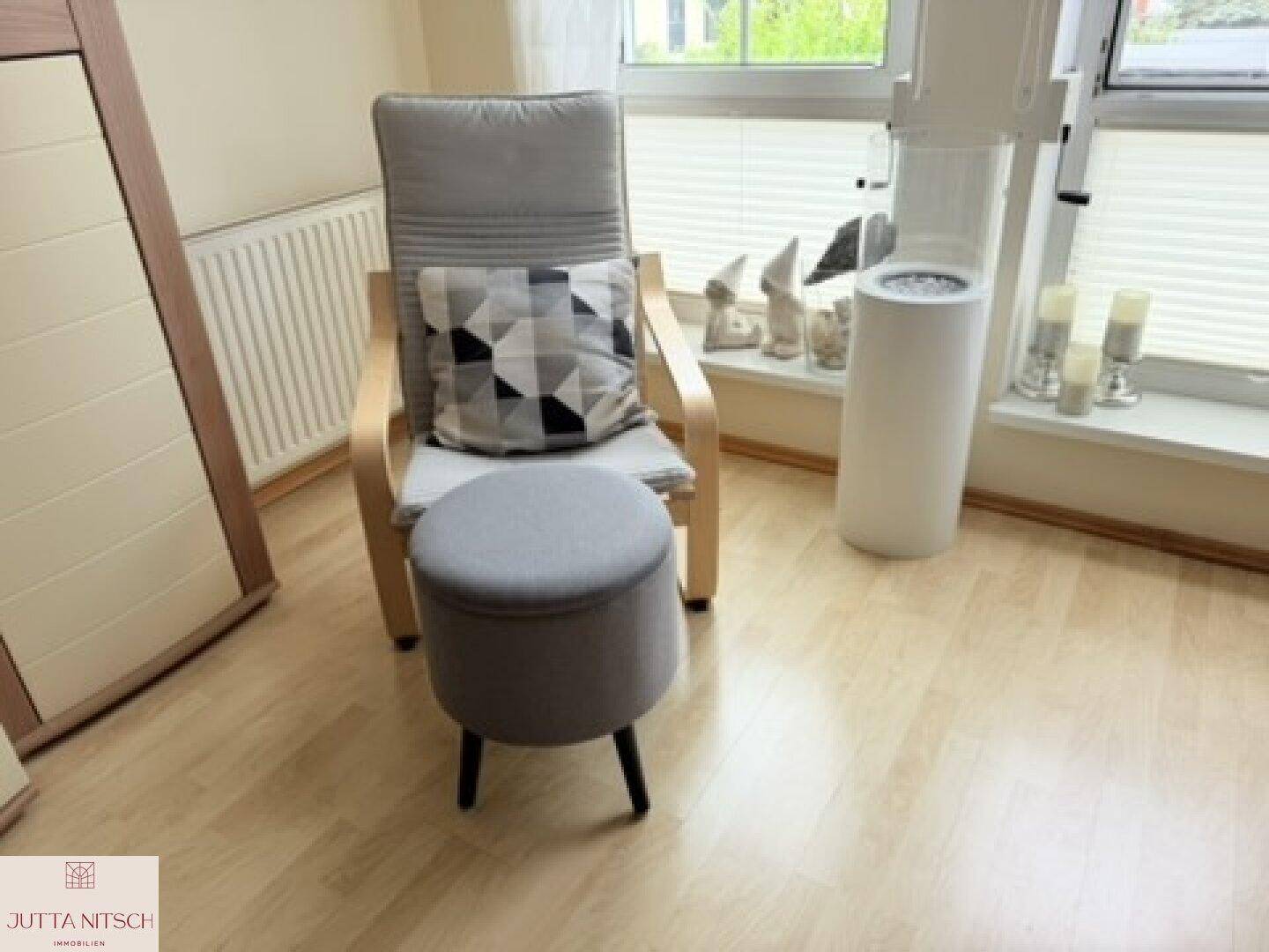 Gemütlicher Sessel am Fenster im Wohnzimmer, ideal zum Entspannen und Lesen.
