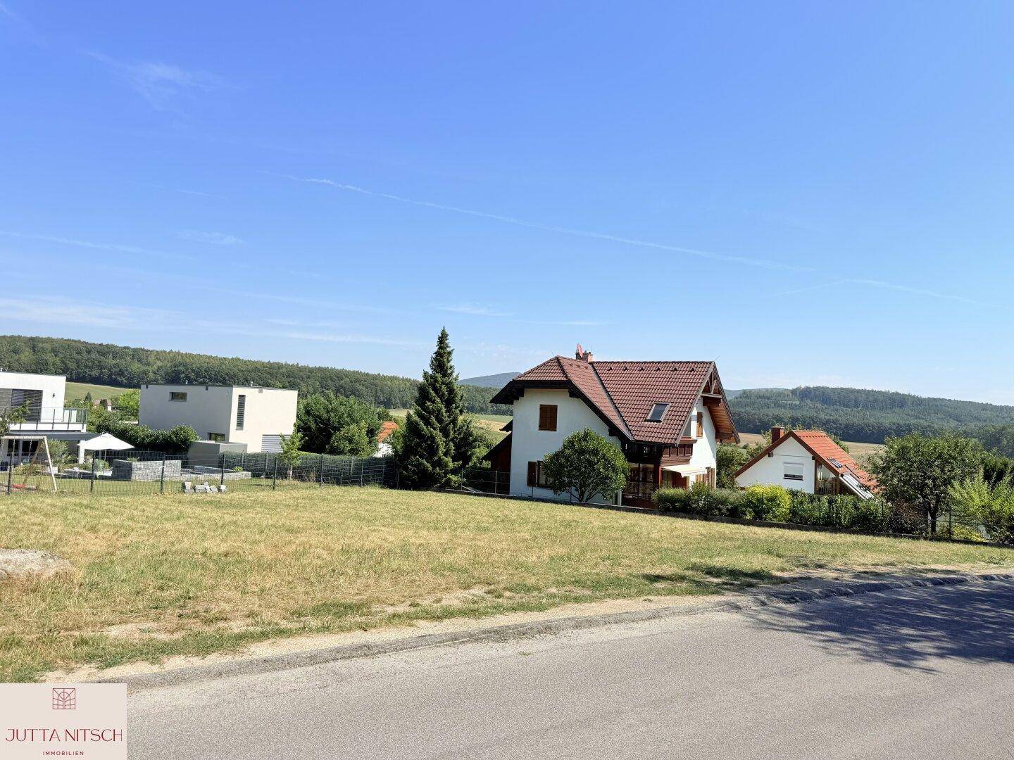 Offenes Grundstück mit Fernblick auf traditionelle und moderne Häuser in ländlicher Umgebung.