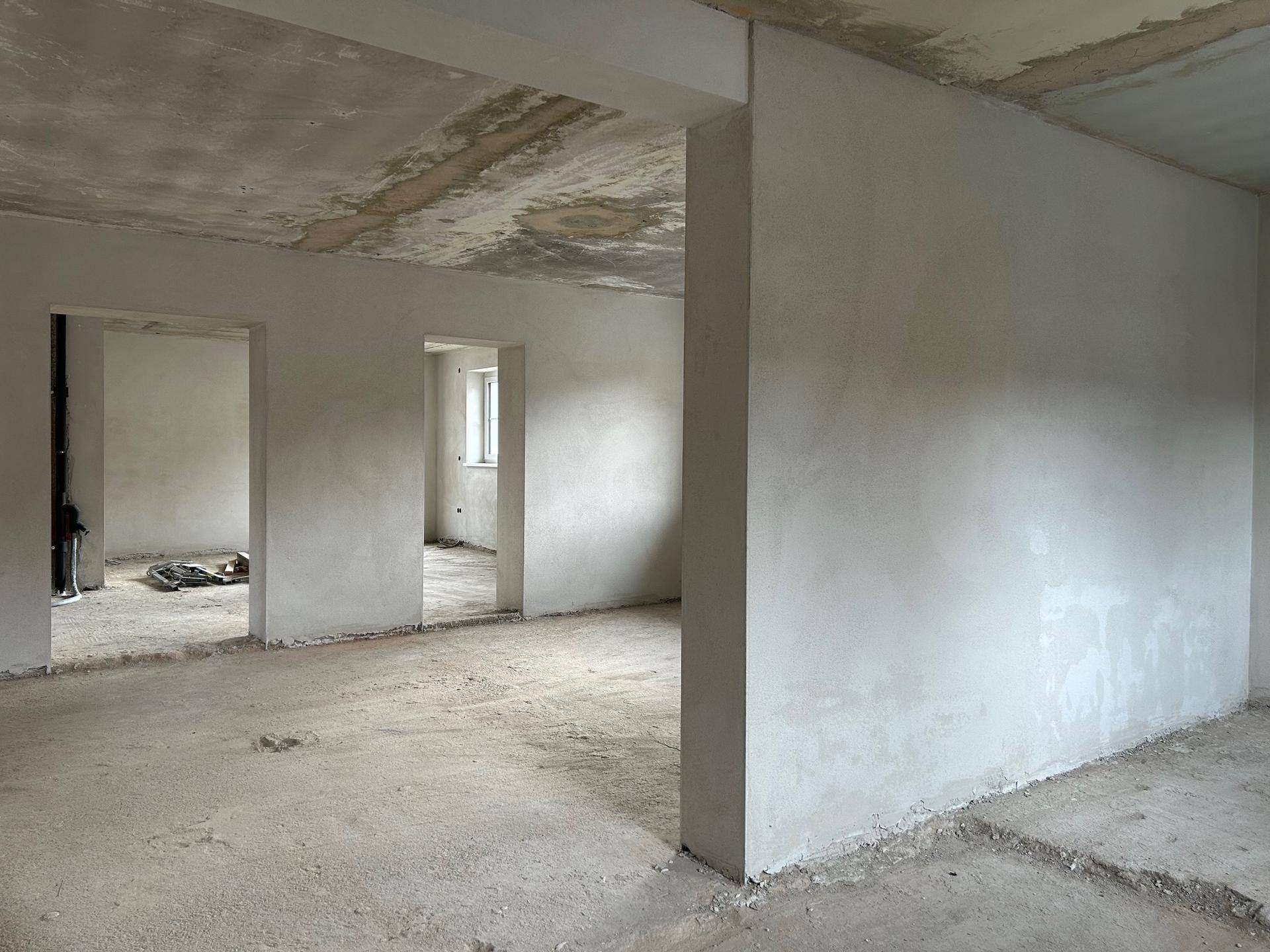 Unfertiger Innenraum mit rohem Betonboden und unverputzten Wänden, bereit für den individuellen Ausbau.