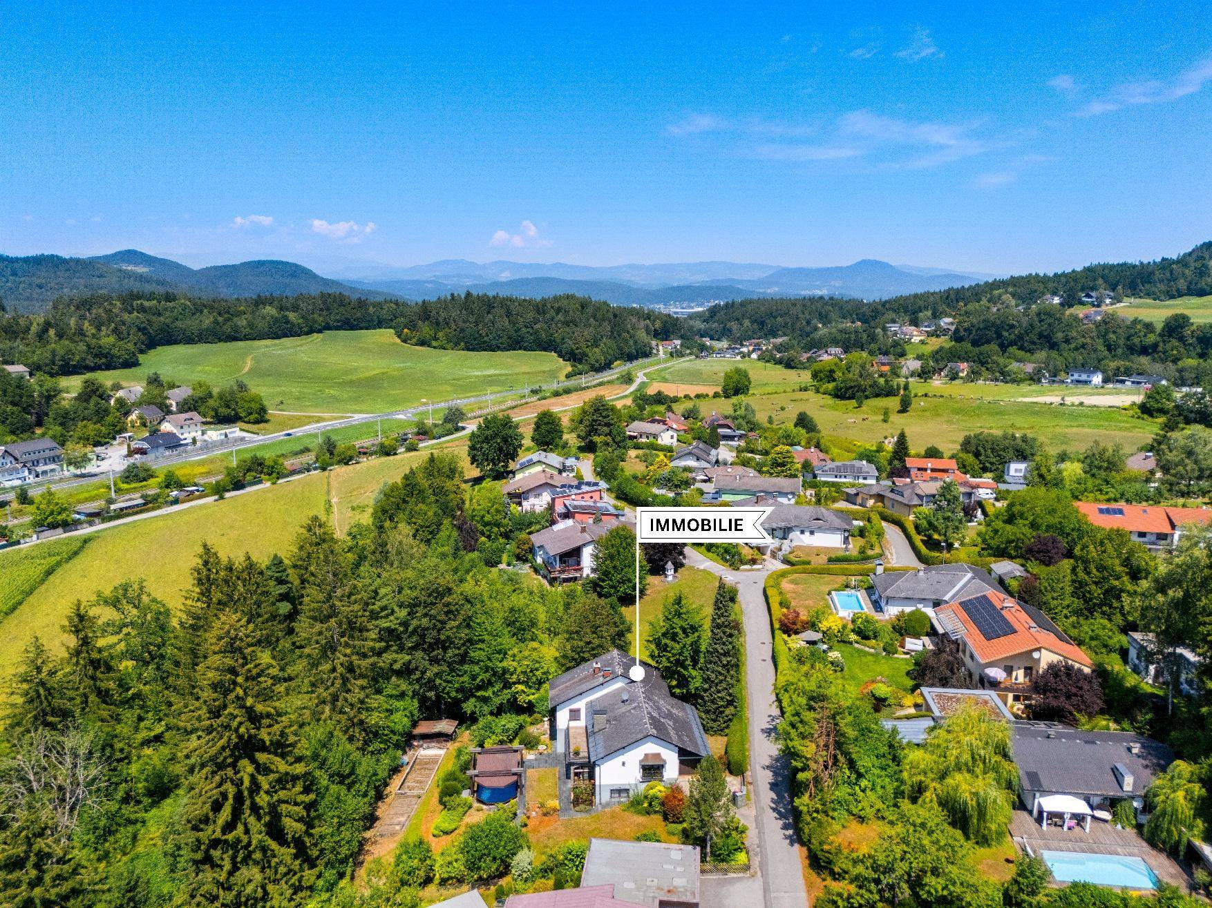 Luftaufnahme der Immobilie in einer ländlichen Umgebung mit viel Grün und Bergen im Hintergrund.