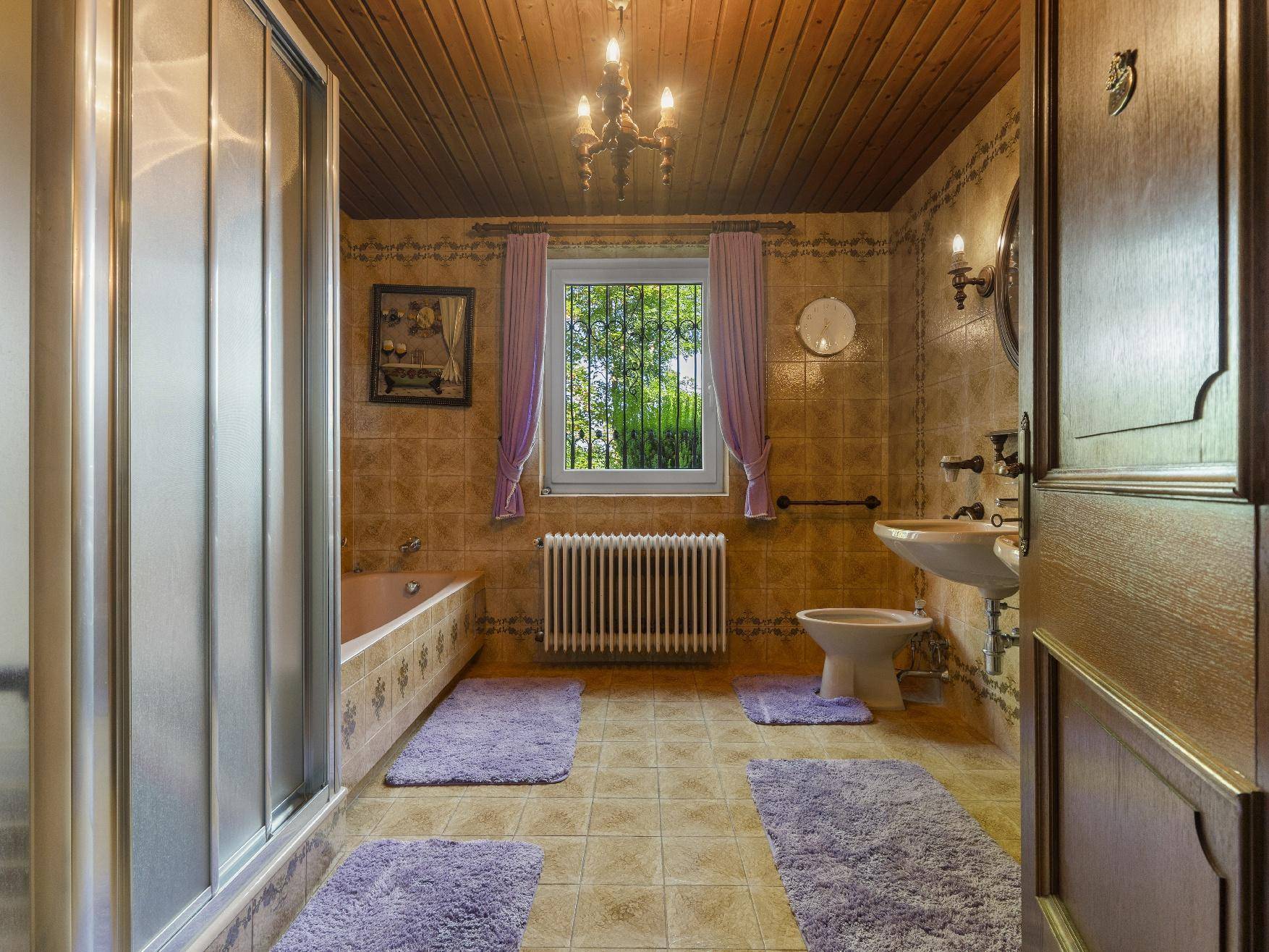 Badezimmer im 80er-Jahre-Stil mit Badewanne, Dusche und Holzdecke.
