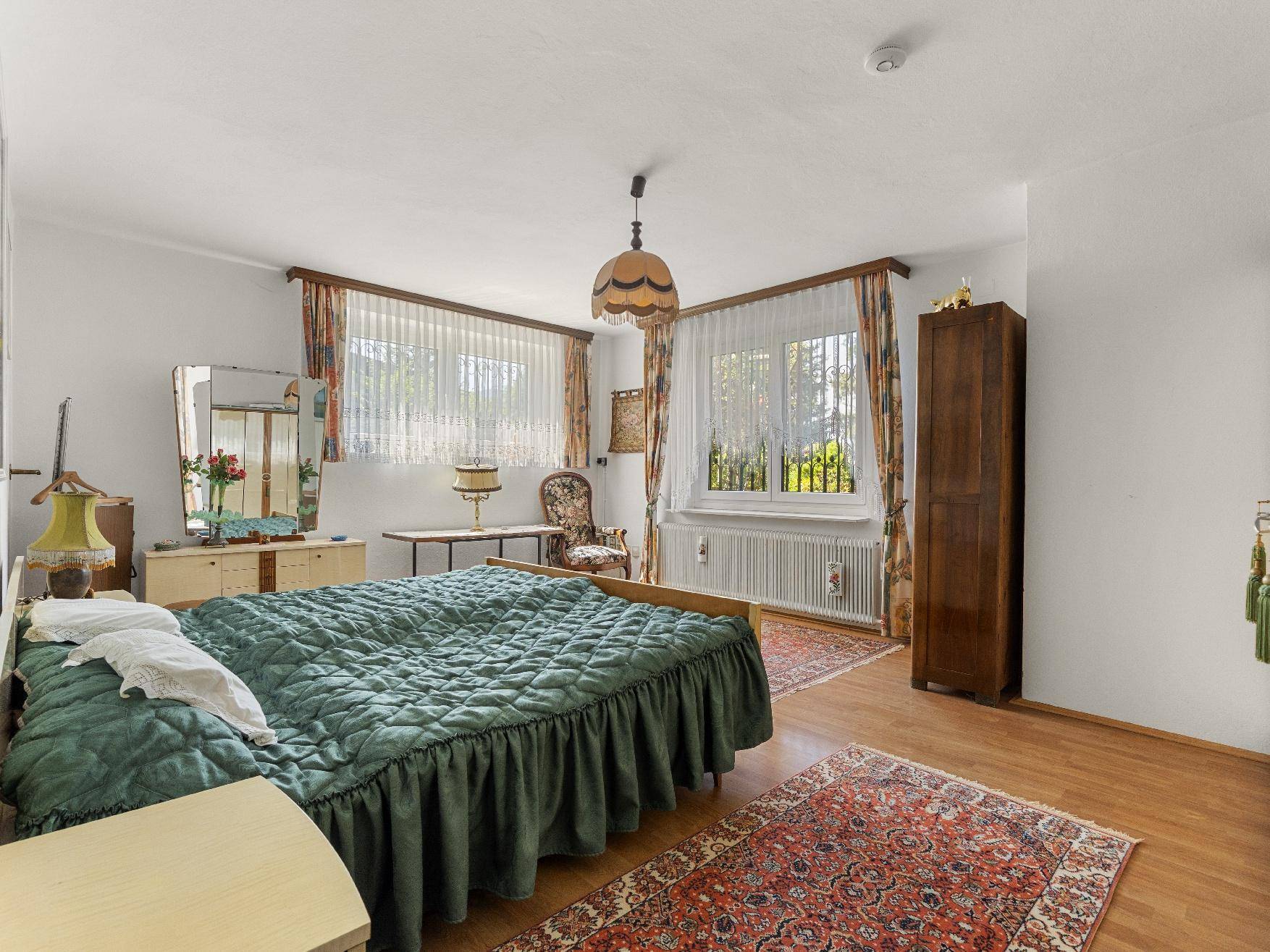 Geräumiges Schlafzimmer mit zwei Einzelbetten, Laminatboden und großen Fenstern.
