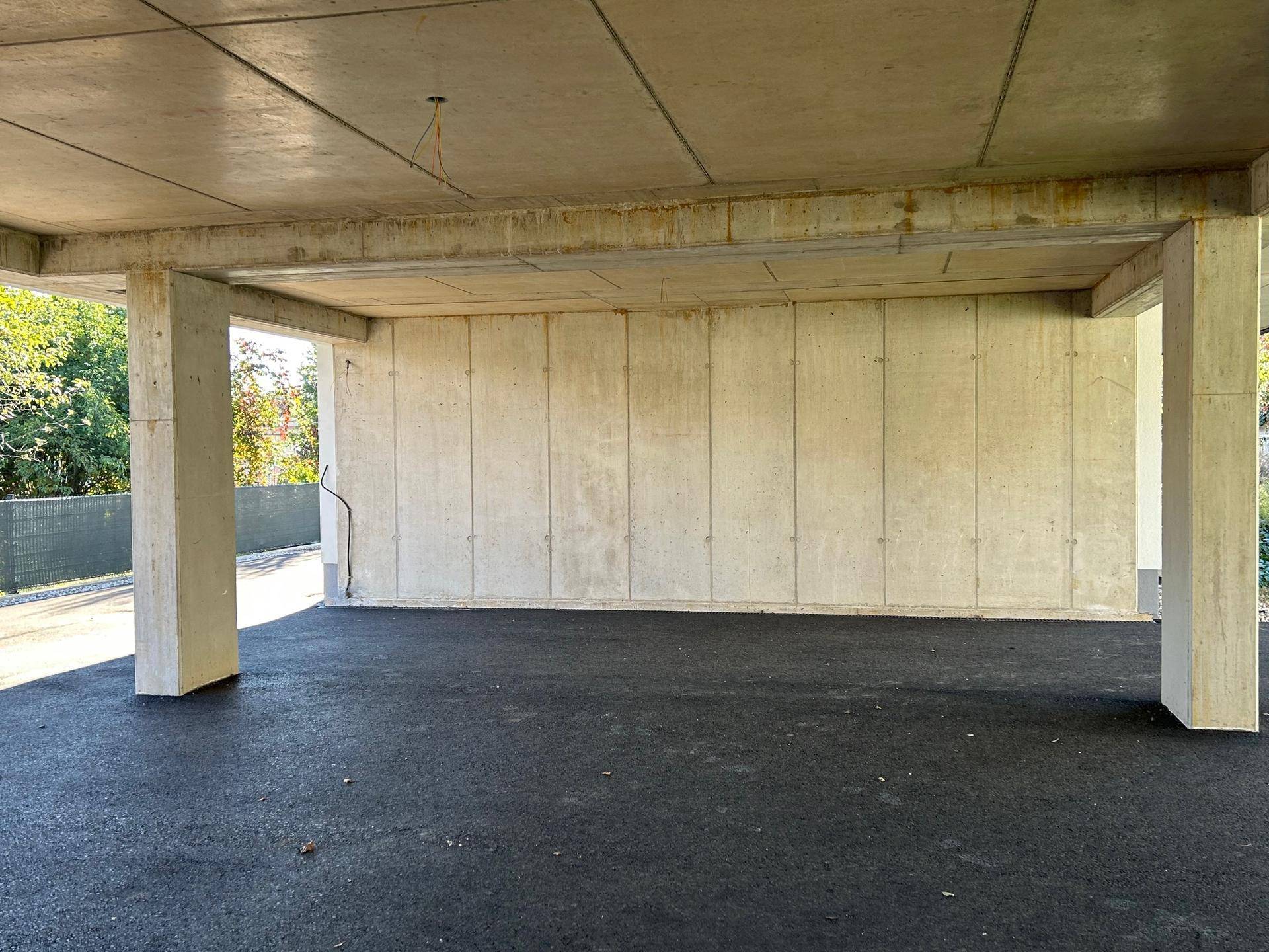Detailansicht des überdachten Parkbereichs mit sichtbaren Betonwänden und tragenden Säulen.