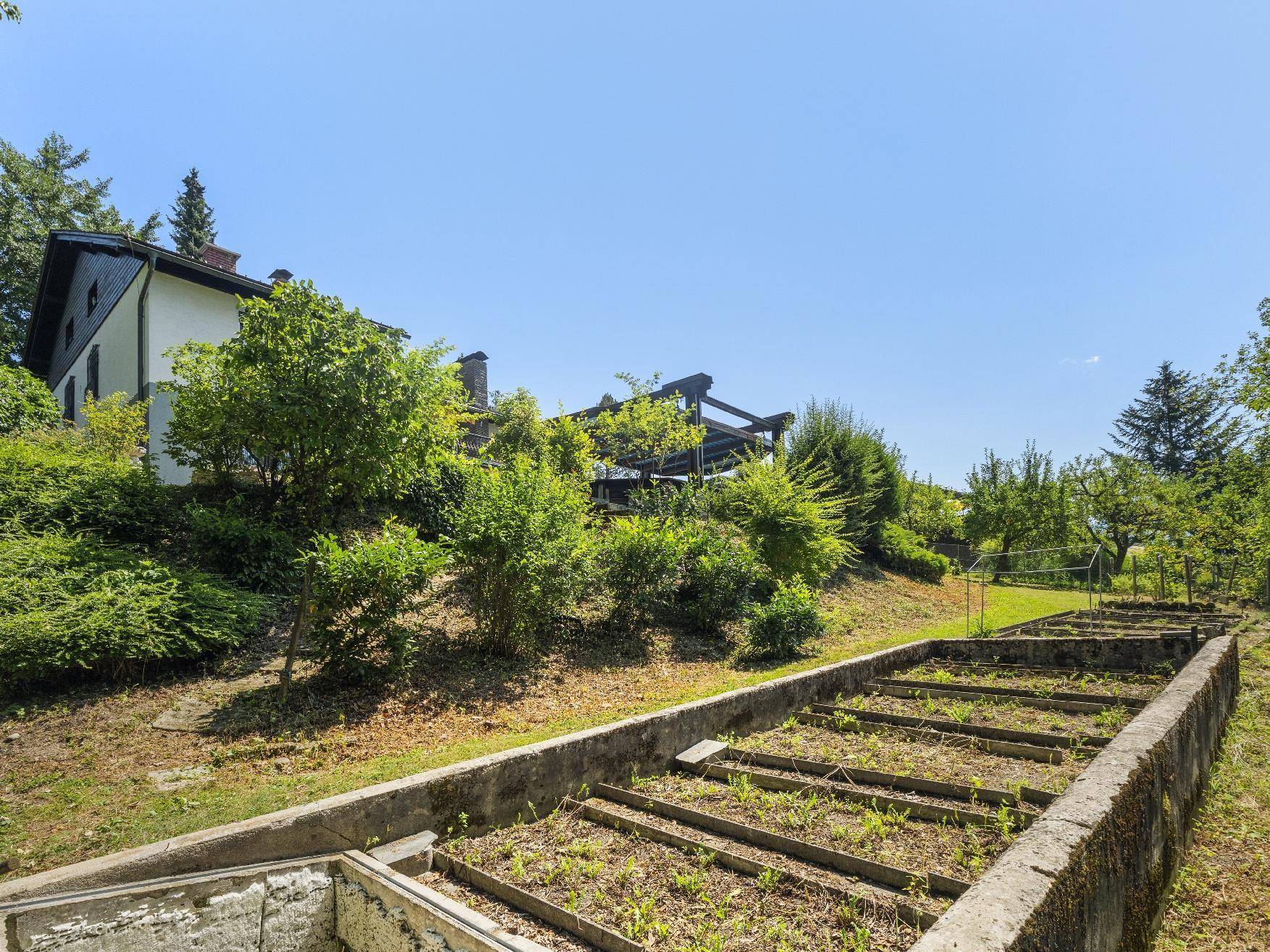 Terrassierter Gartenbereich mit Hochbeeten, ideal für den Anbau von Gemüse und Kräutern.