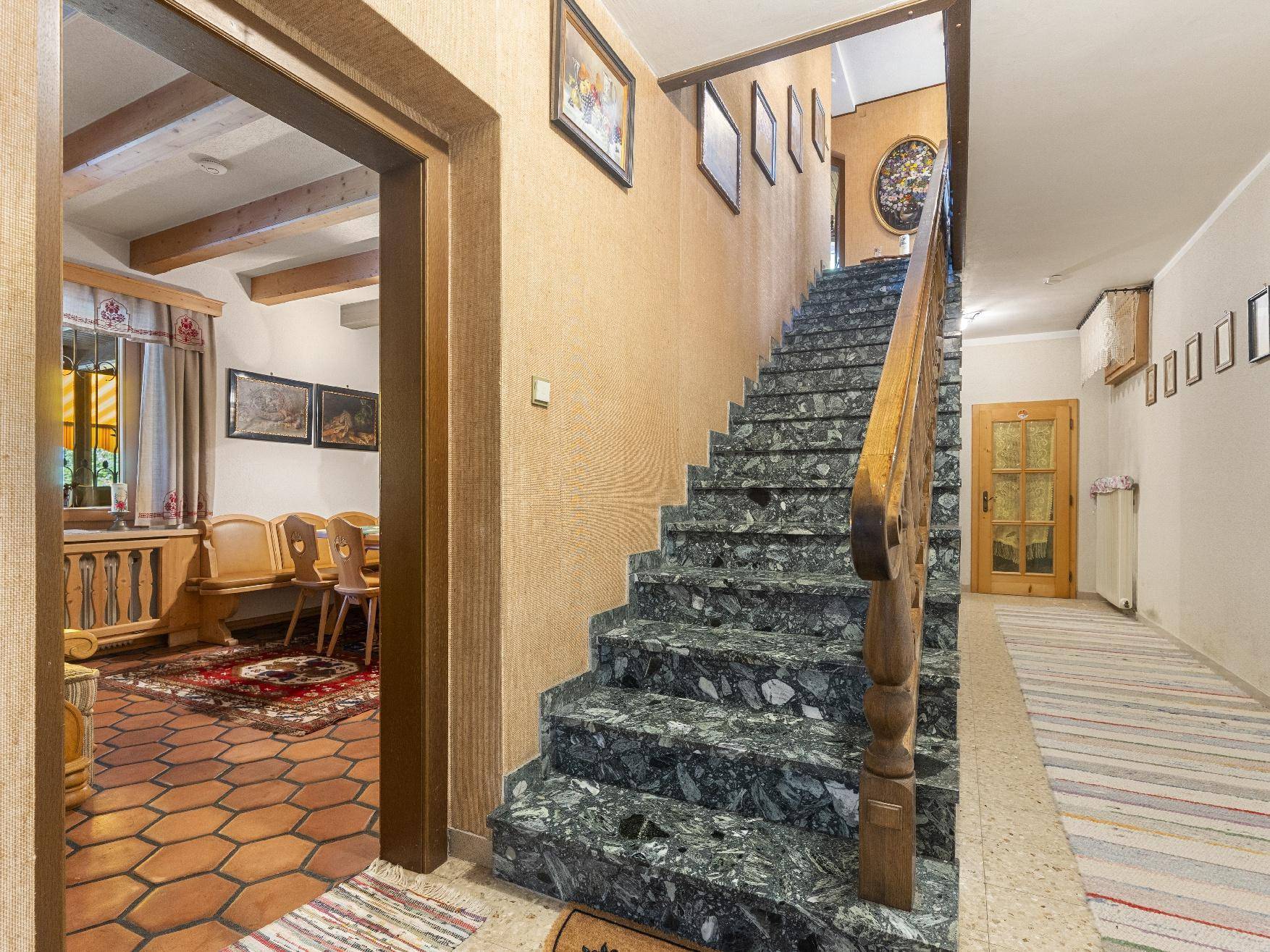 Treppenhaus mit Marmorstufen, Holzgeländer und Zugang zu verschiedenen Ebenen.