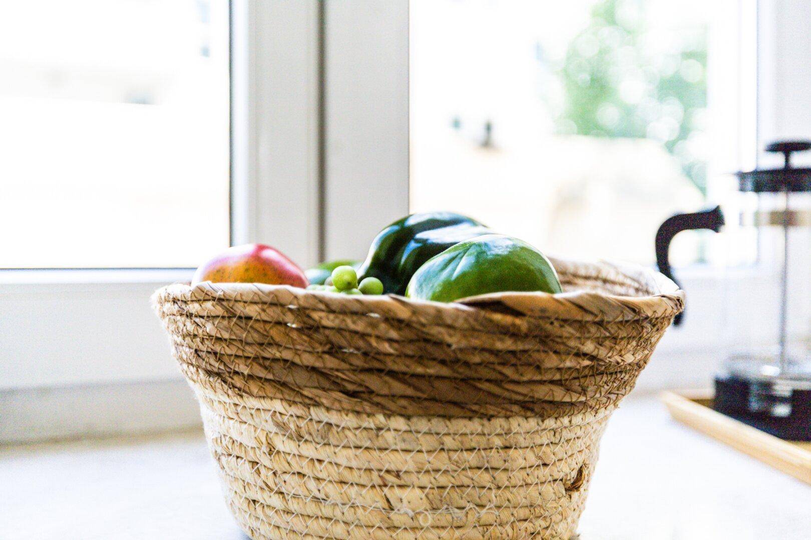 Korb mit frischem Obst auf der Fensterbank in der Küche, mit Blick ins Grüne.