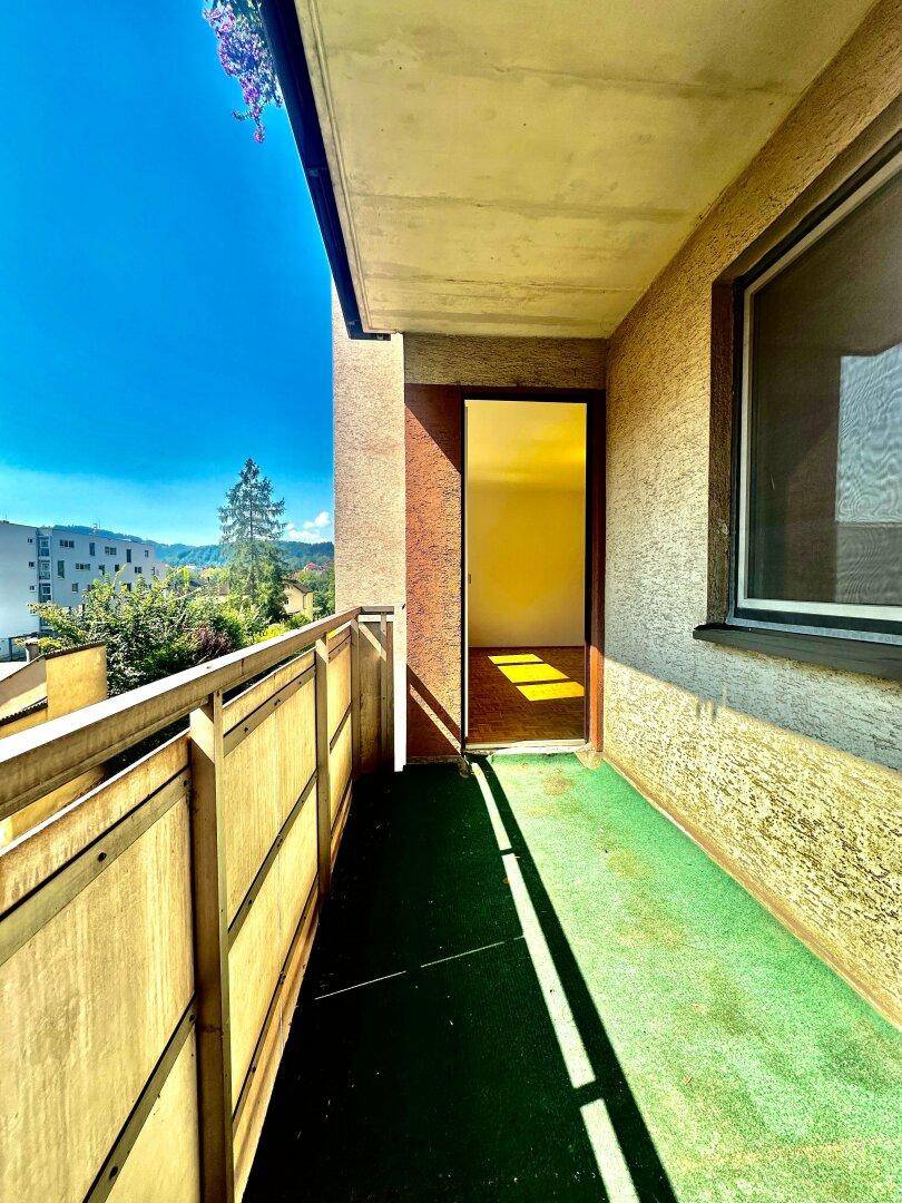 Balkon mit grünem Bodenbelag und Zugang zu einem hellen Innenraum, mit Weitblick.