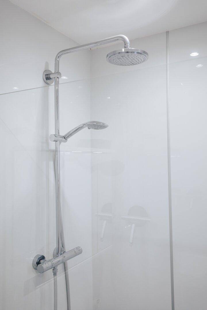 Detailansicht der modernen Duscharmatur mit Regenduschkopf und Handbrause.