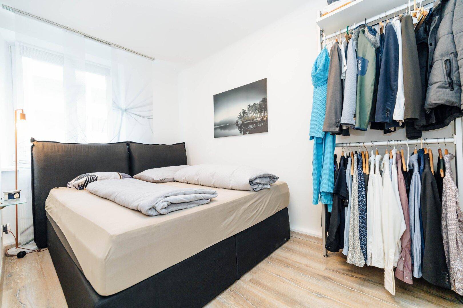 Gemütliches Schlafzimmer mit Doppelbett, hellem Laminatboden und offenem Kleiderschranksystem.