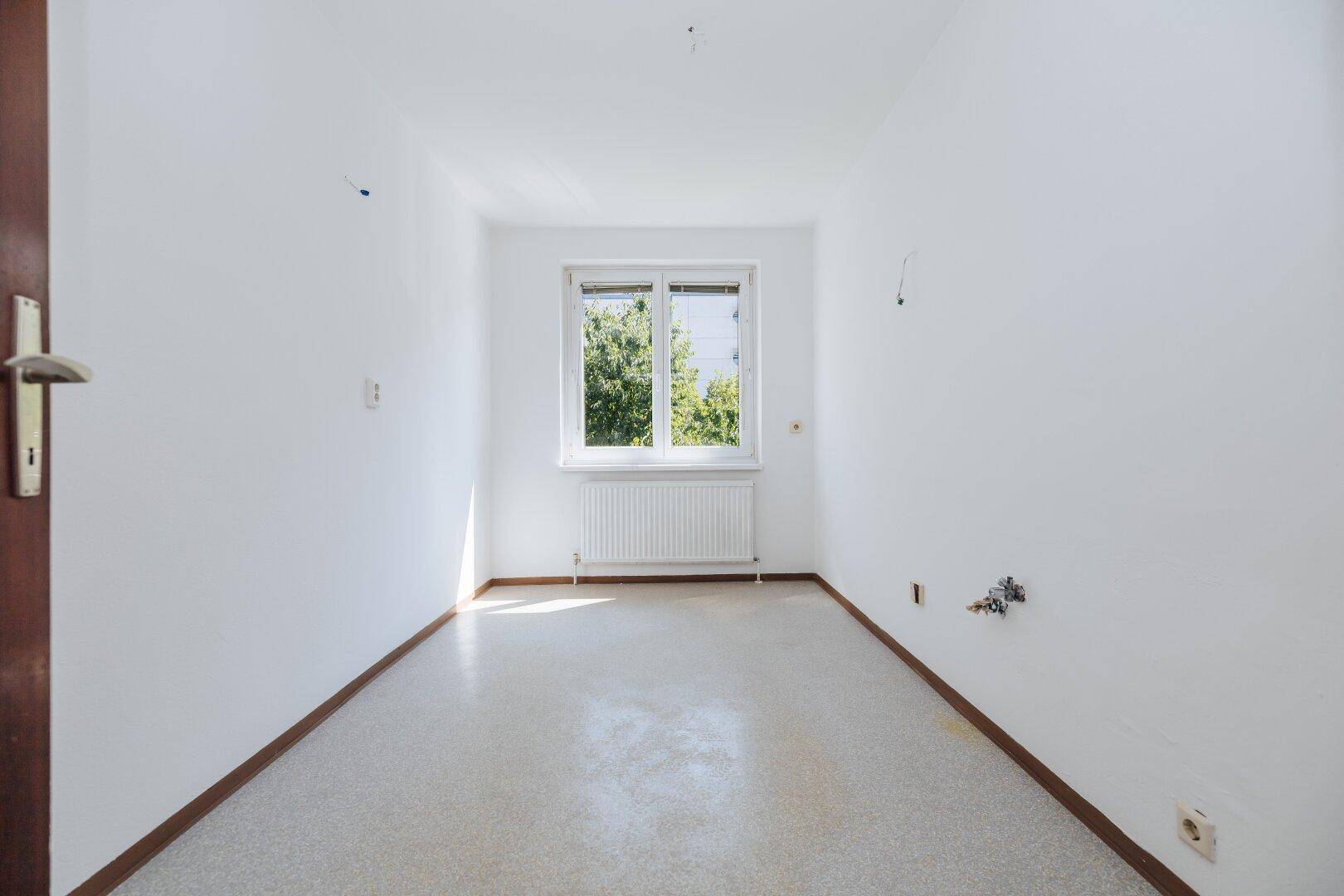 Kleiner, heller Raum mit Linoleumboden und Fenster, möglicherweise für eine Küche.