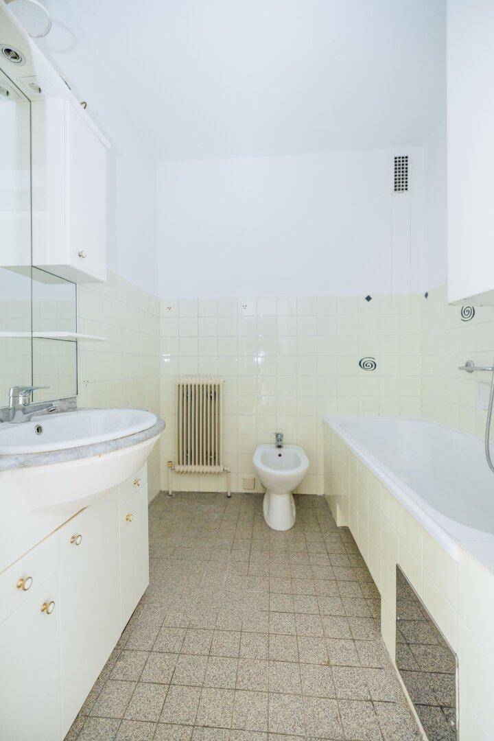 Badezimmer mit Badewanne, Bidet, Waschbecken und hellgrünen Wandfliesen.