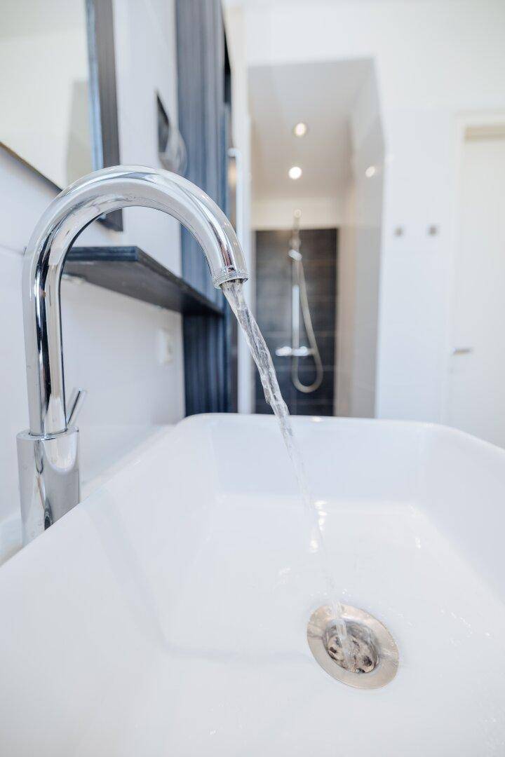 Modernes Waschbecken mit Chromarmatur und fließendem Wasser in einem Badezimmer.