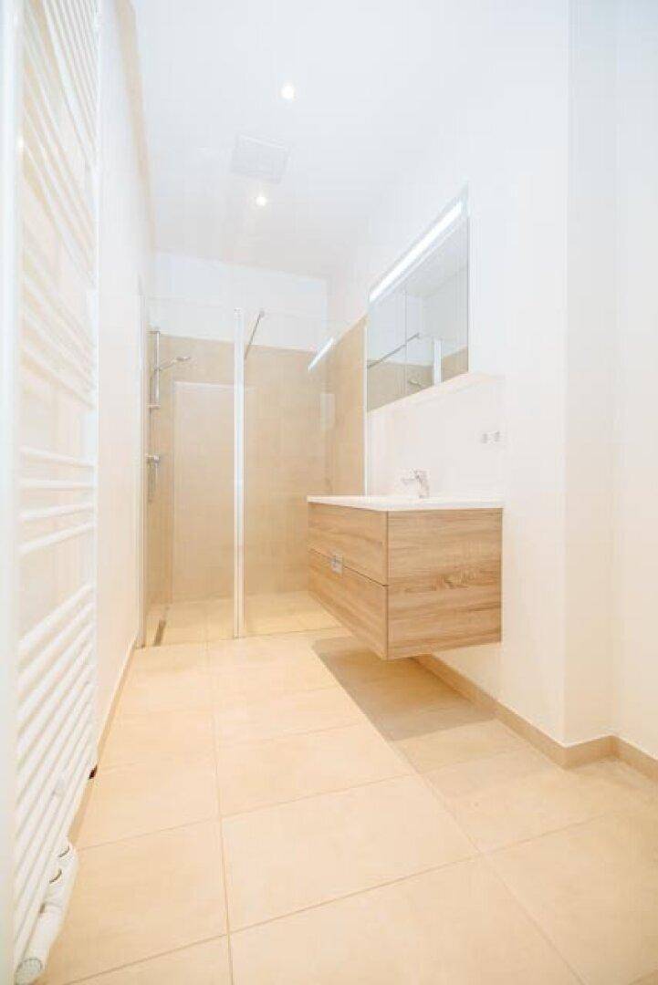 Modernes Badezimmer mit begehbarer Dusche, schwebendem Waschtisch und beheiztem Handtuchhalter.