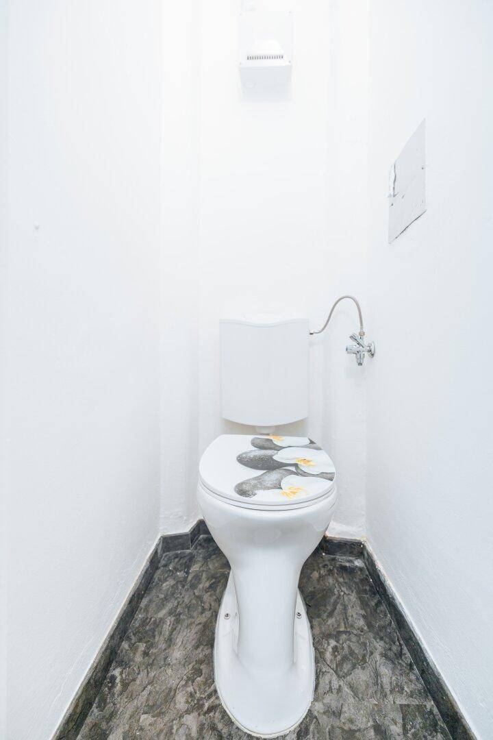 Kleines separates WC mit Toilette und dunklem Fliesenboden in schlichtem Design.