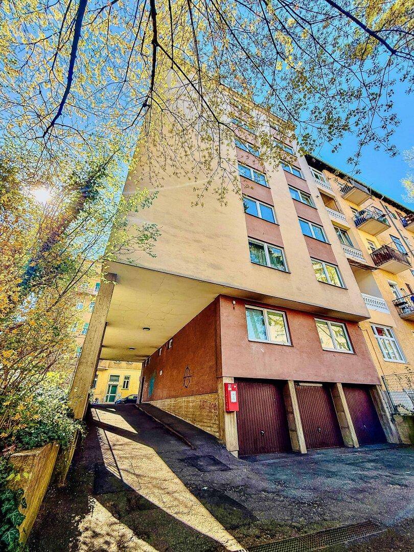 Mehrstöckiges Wohngebäude mit Balkonen und Garagenzufahrt.