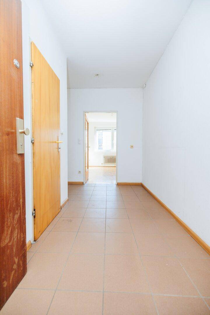 Geräumiger Flur mit Fliesenboden und Holztüren, der zu den Wohnräumen führt.