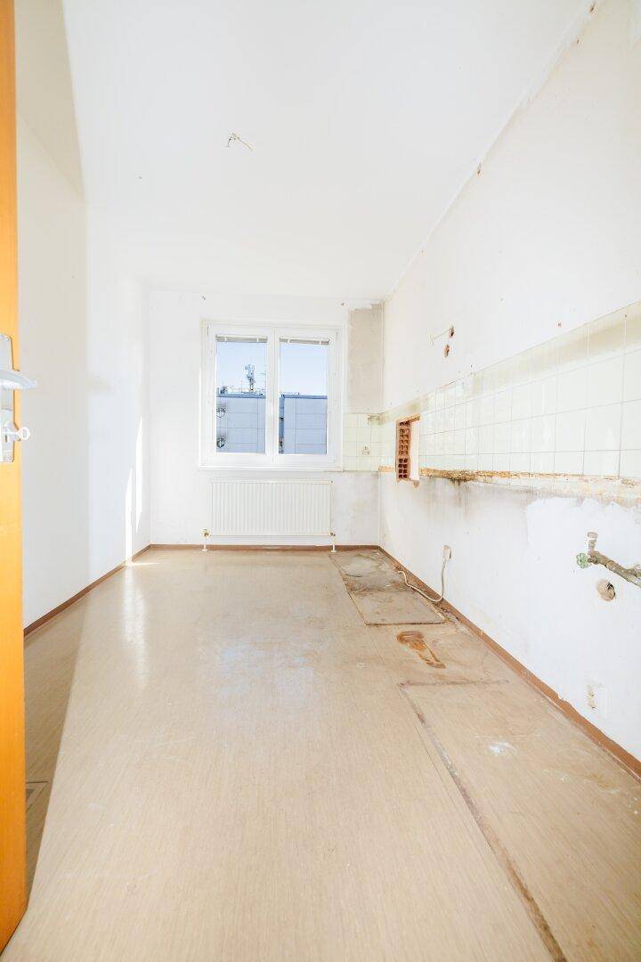 Leere Küche mit Anschlüssen für Einbauten und Fenster, bereit für individuelle Gestaltung.