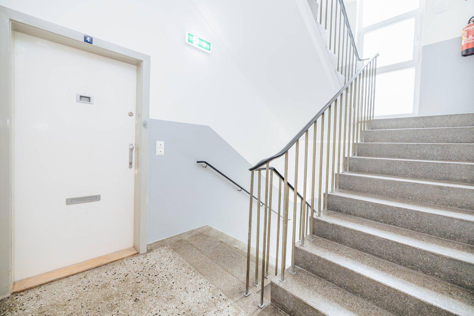 Treppenhaus mit Steinstufen und Metallgeländer, führt zu den verschiedenen Etagen des Gebäudes.