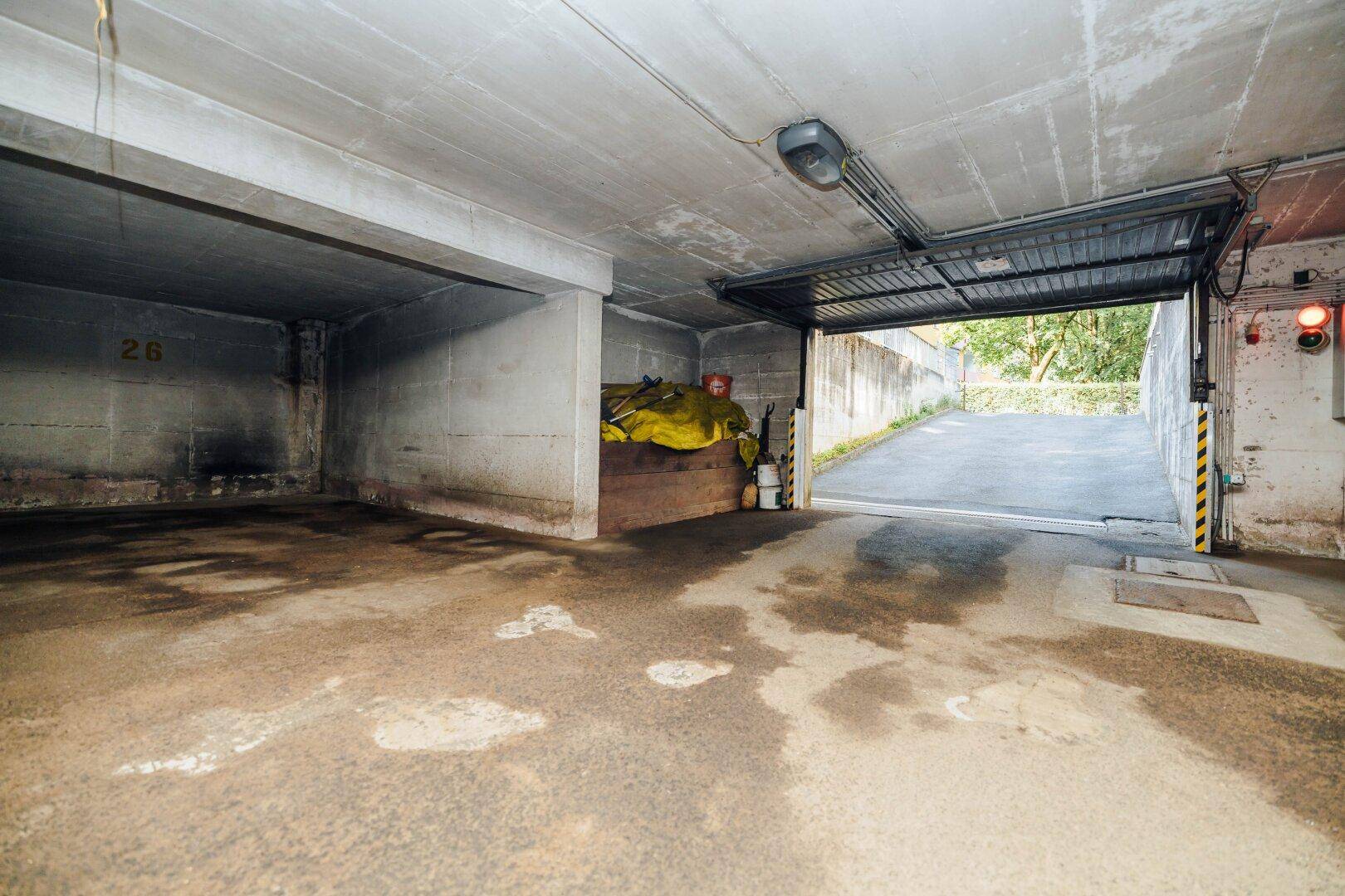 Geräumige Tiefgarage mit Betonwänden und offenem Tor zur Ausfahrt.