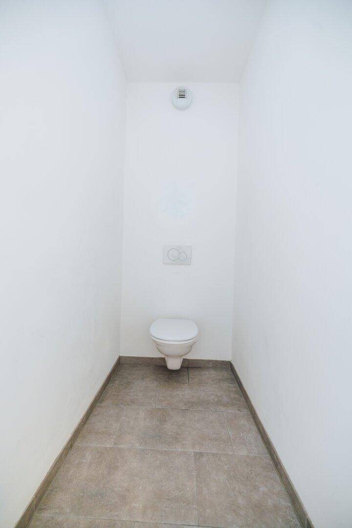 Kleines, separates WC mit Wand-WC und Fliesenboden, funktional und sauber gestaltet.