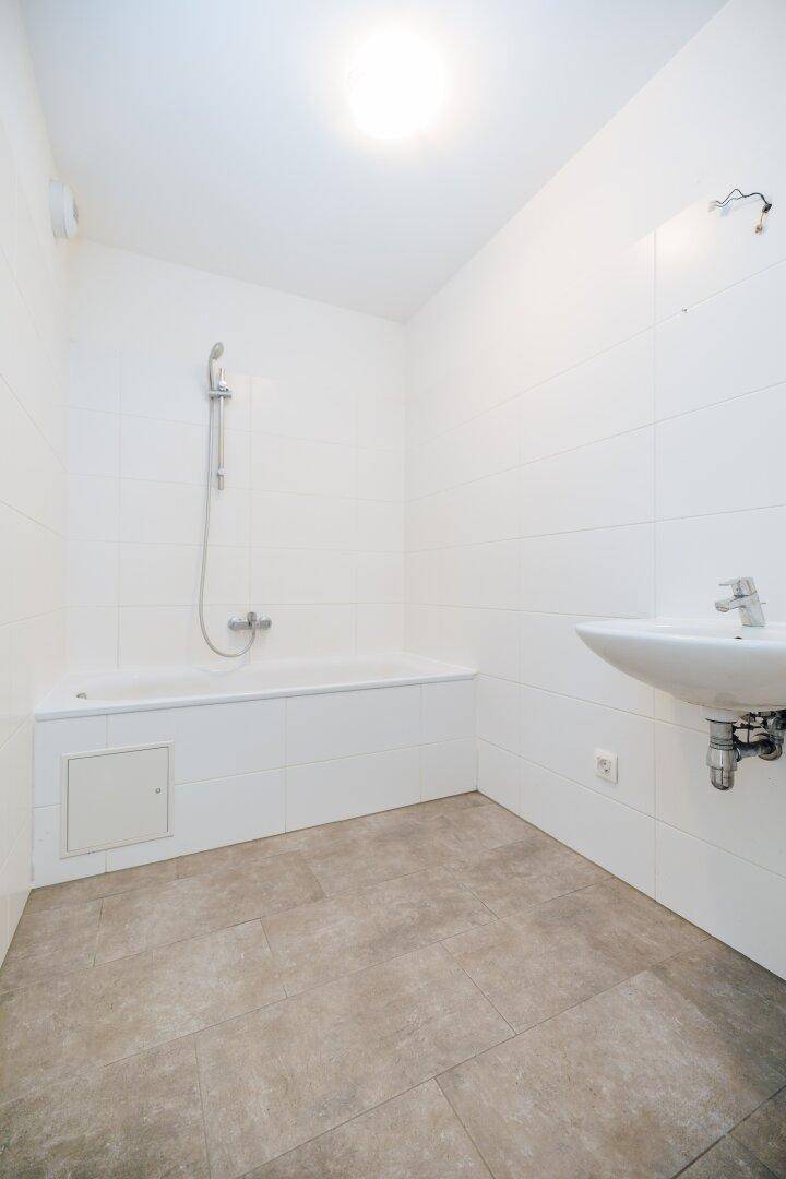 Helles Badezimmer mit Badewanne, Waschbecken und Fliesenboden, modern und pflegeleicht.