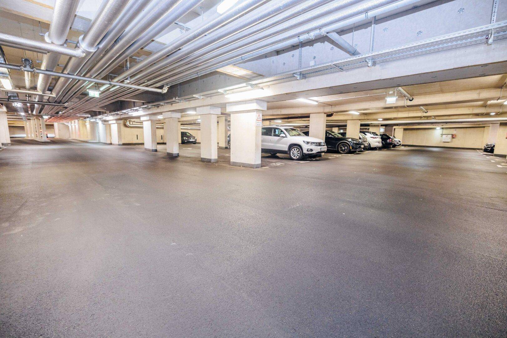 Geräumige Tiefgarage mit mehreren Stellplätzen und guter Beleuchtung für Fahrzeuge.