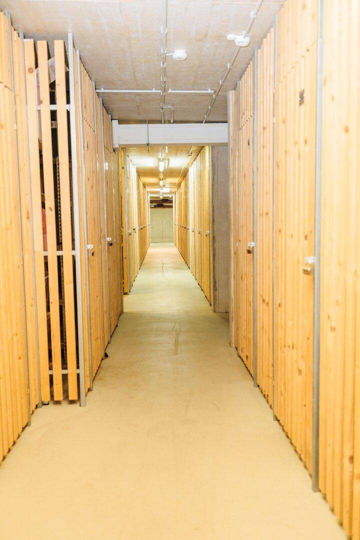 Langer Kellergang mit zahlreichen Holzverschlägen für zusätzlichen Stauraum.