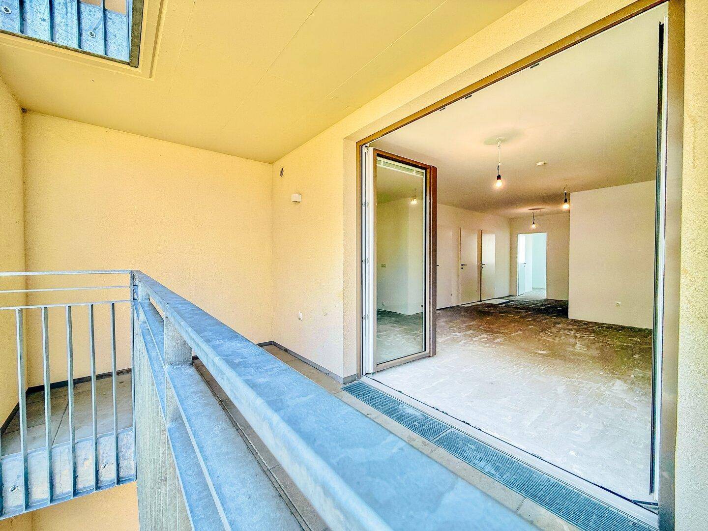 Geräumiger Balkon mit Fliesenboden und Zugang zum hellen Innenbereich der Wohnung.