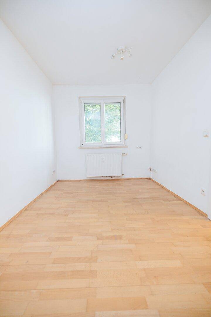 Geräumiger, heller Raum mit Holzboden und einem Fenster, das eine angenehme Atmosphäre schafft.