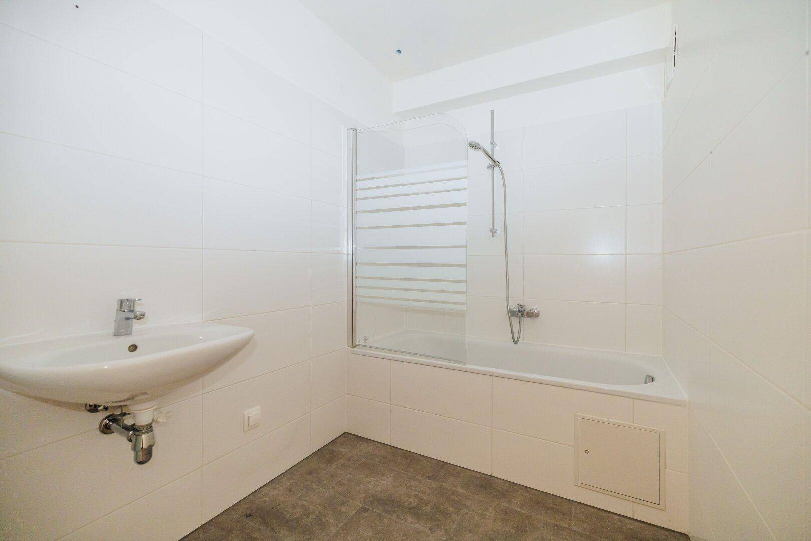 Modernes Badezimmer mit Badewanne, Duschabtrennung und weiß gefliesten Wänden.