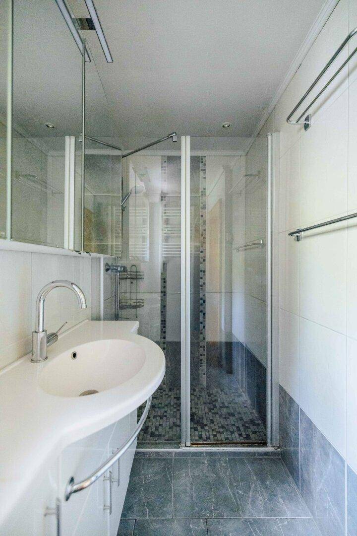 Helles Badezimmer mit Duschkabine, modernem Waschtisch und Spiegelschrank.