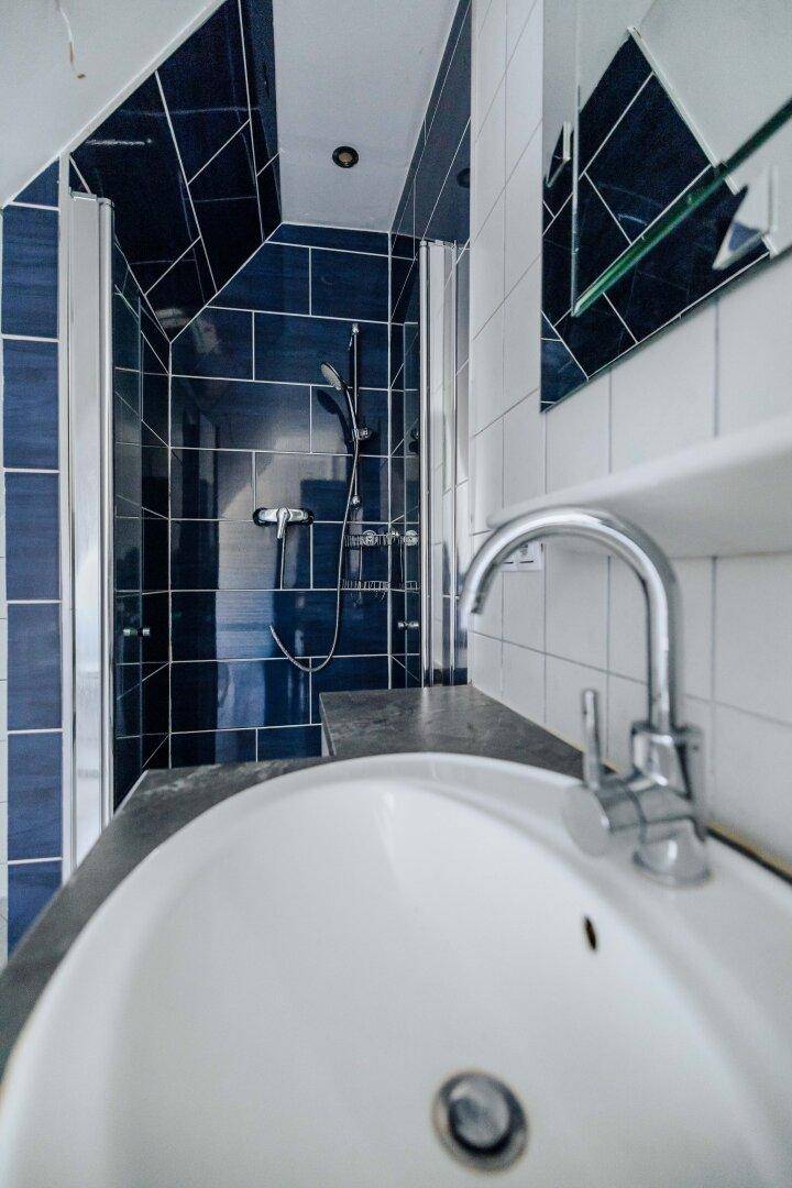 Duschbereich mit blauen Fliesen und moderner Armatur im Dachgeschossbad.