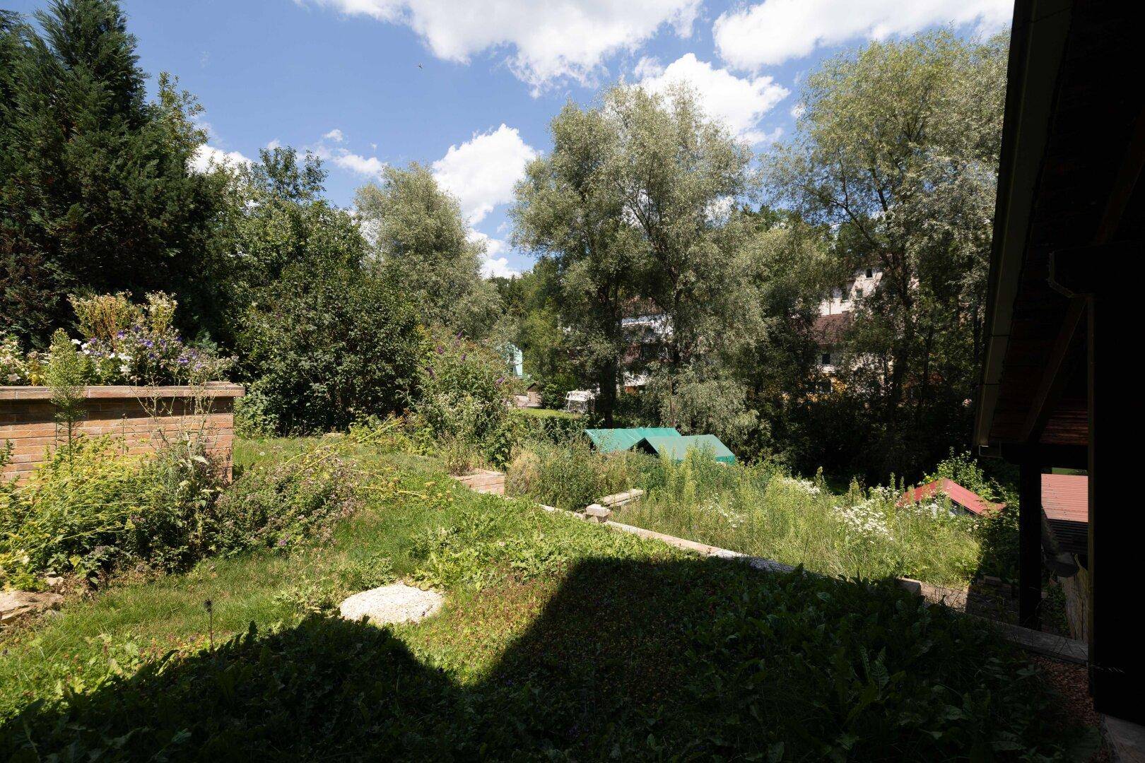 Weitläufiger Gartenbereich mit viel Grün, Bäumen und Blick in die Umgebung.