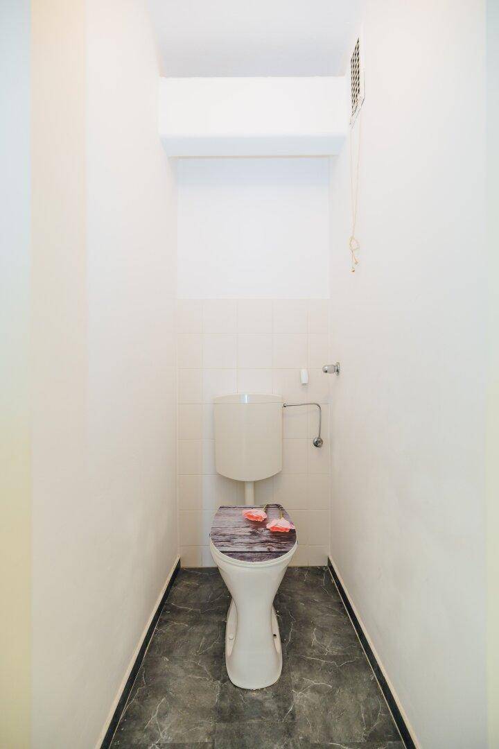 Separates WC mit Toilette und dunklem Fliesenboden, ideal für Gäste.