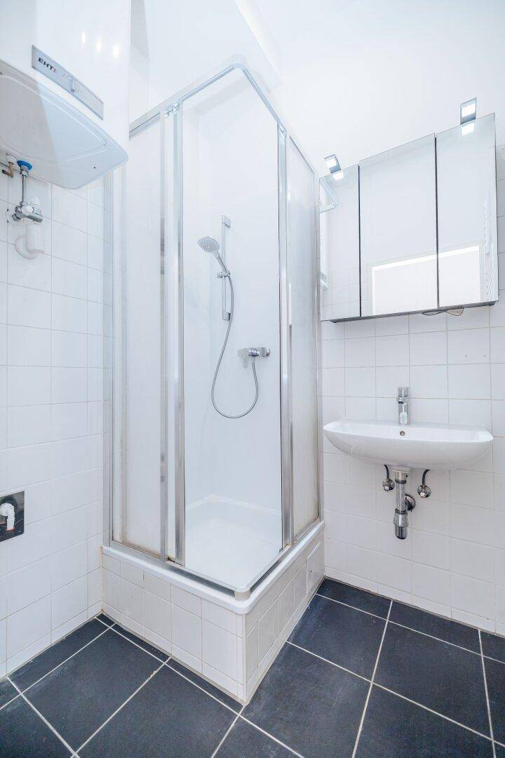 Funktionales Badezimmer mit praktischer Duschkabine, Waschbecken und Spiegelschrank, in gutem Zustand.