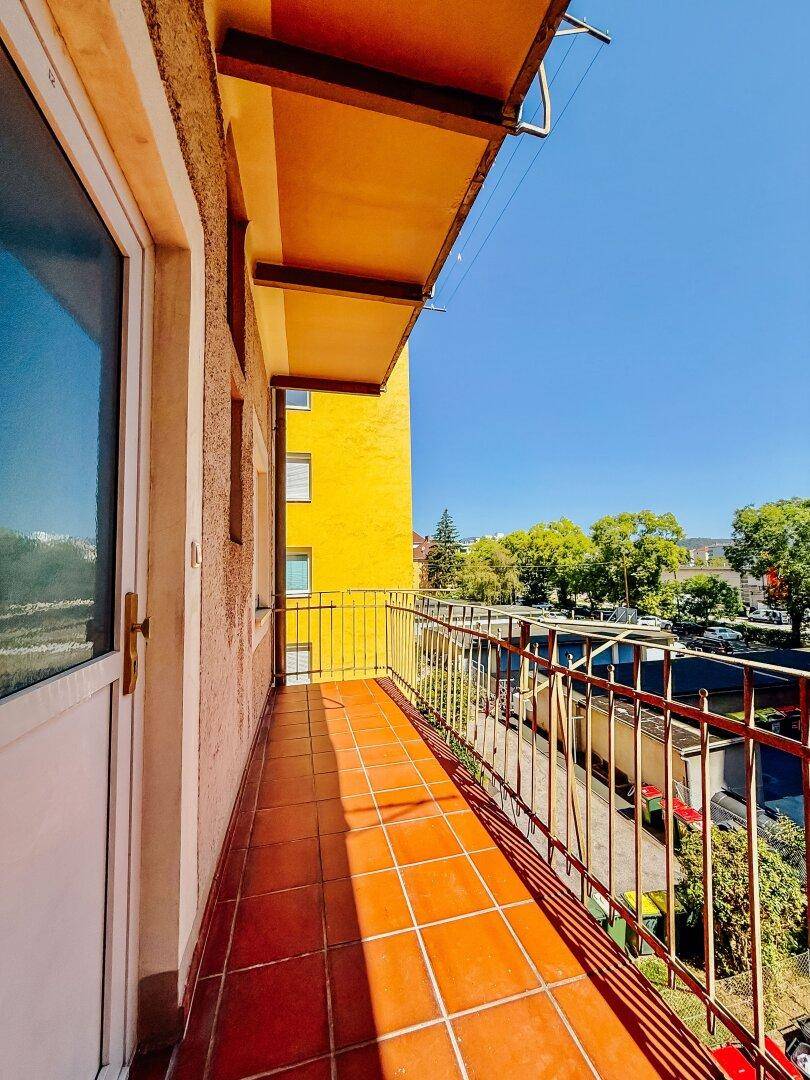 Sonniger Balkon mit Terrakotta-Fliesen und Blick auf die Umgebung.