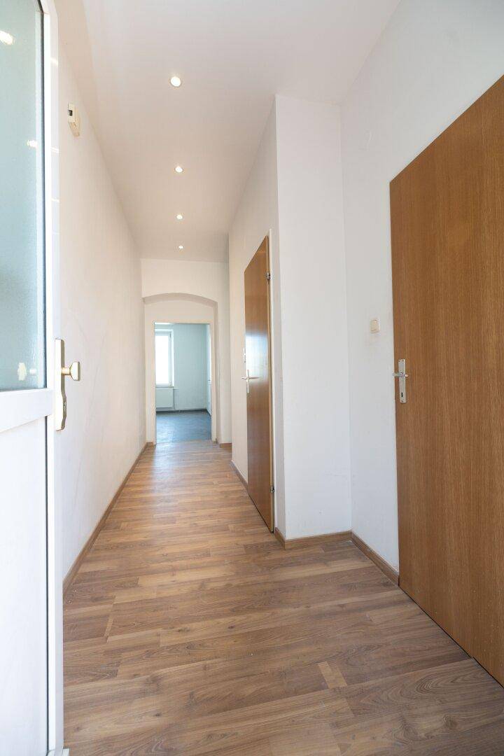 Langer, heller Flur mit Holzboden und mehreren Türen zu den angrenzenden Zimmern.