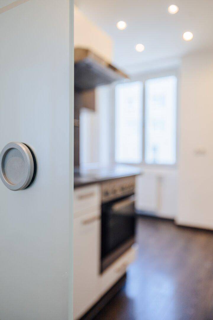 Unscharfer Blick in eine Küche mit Backofen und Kochfeld, durch eine Schiebetür gesehen.