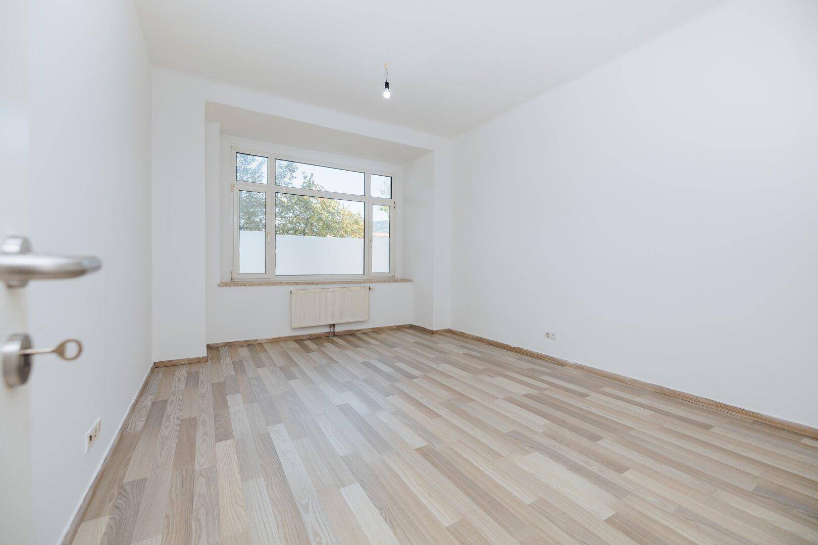 Geräumiges, helles Zimmer mit Laminatboden und Blick ins Grüne, bereit zum Einzug.