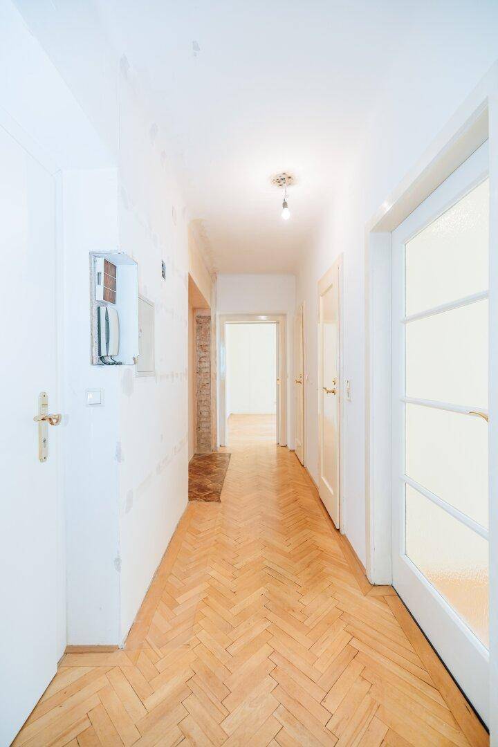 Heller Flur mit Fischgrätparkett und mehreren Türen, der die Räume verbindet.