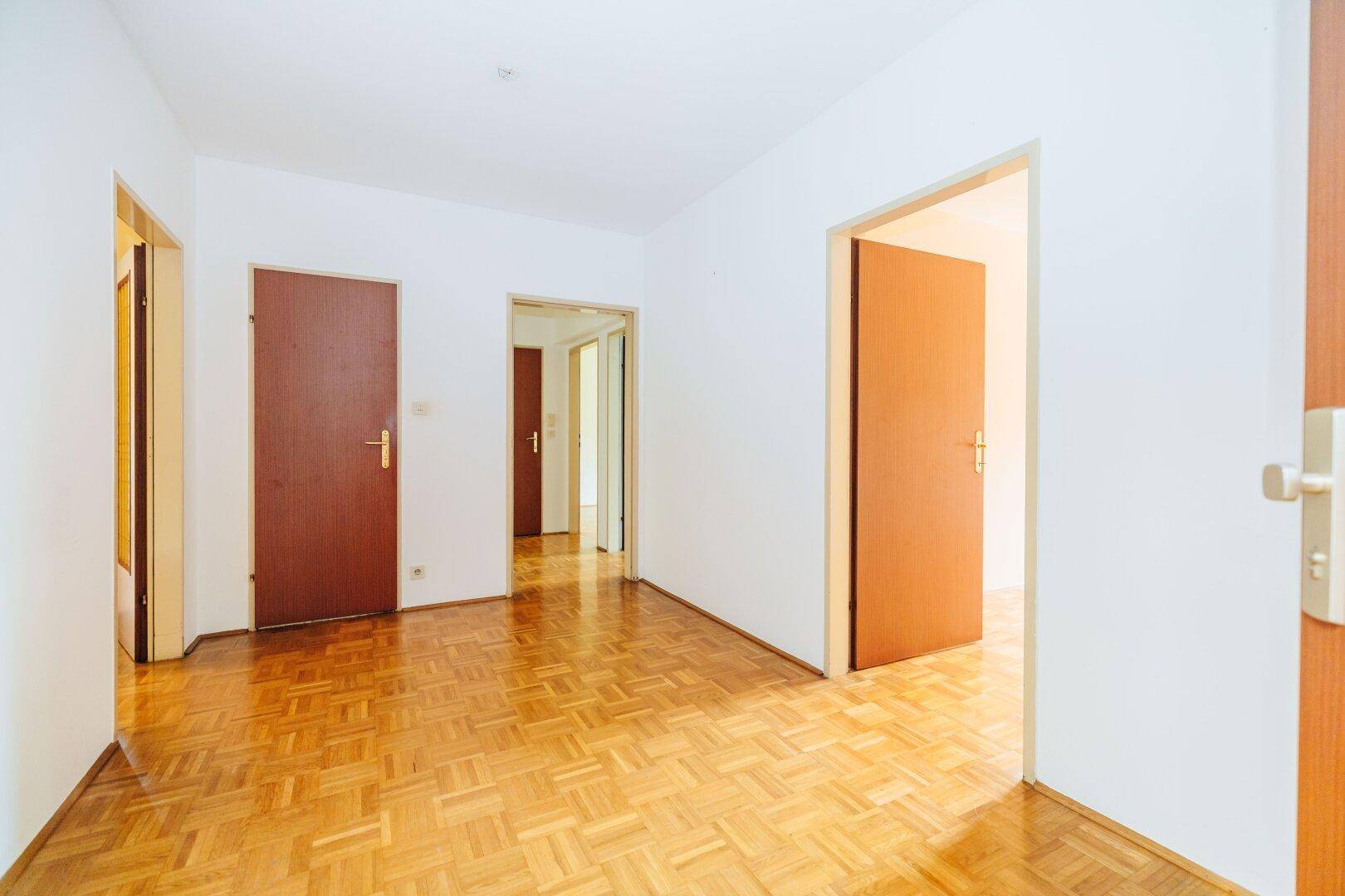 Heller Flur mit Parkettboden und mehreren Türen, der verschiedene Räume der Wohnung verbindet.
