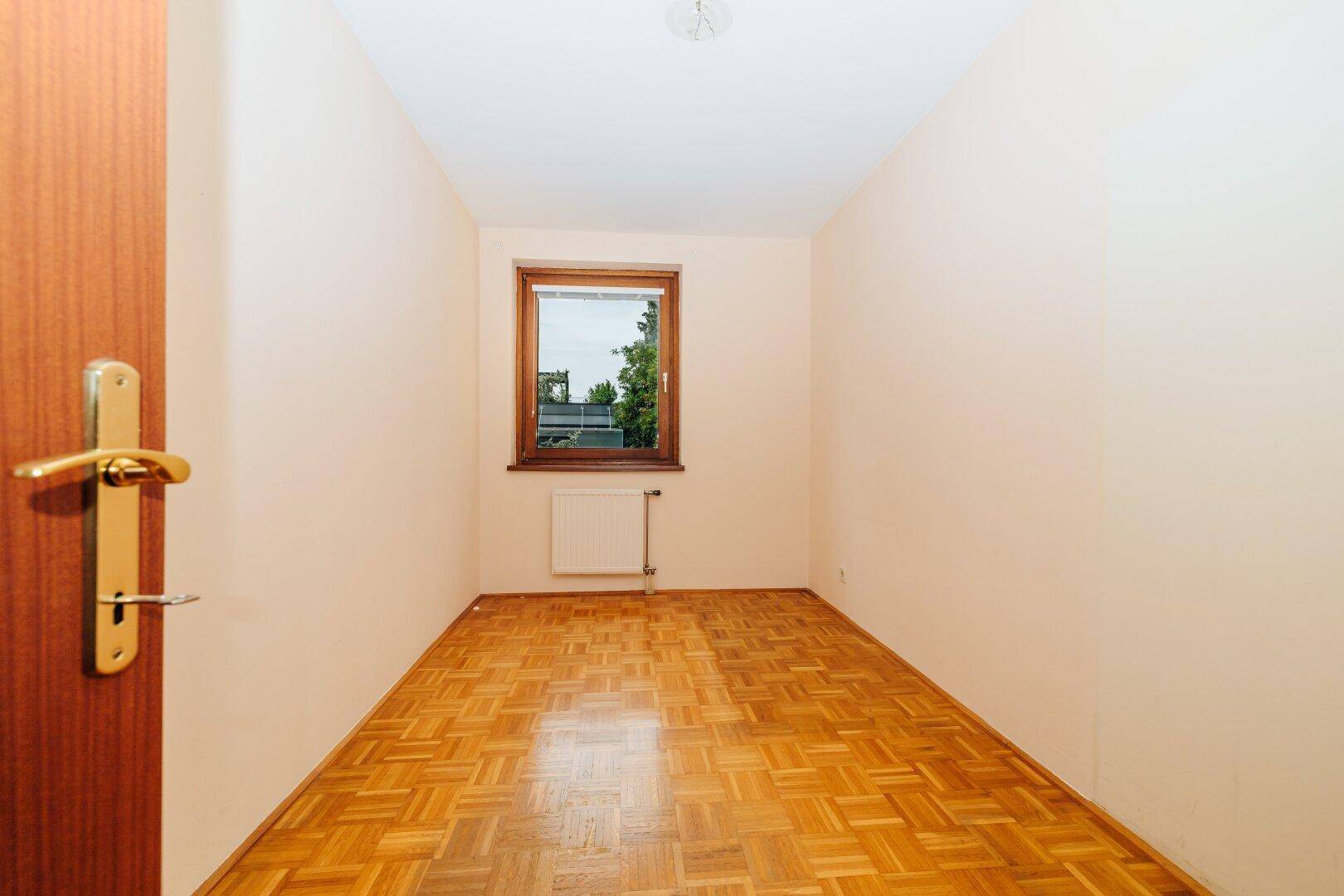 Gemütliches Zimmer mit Parkettboden, hellen Wänden und einem Fenster für natürliche Belichtung.