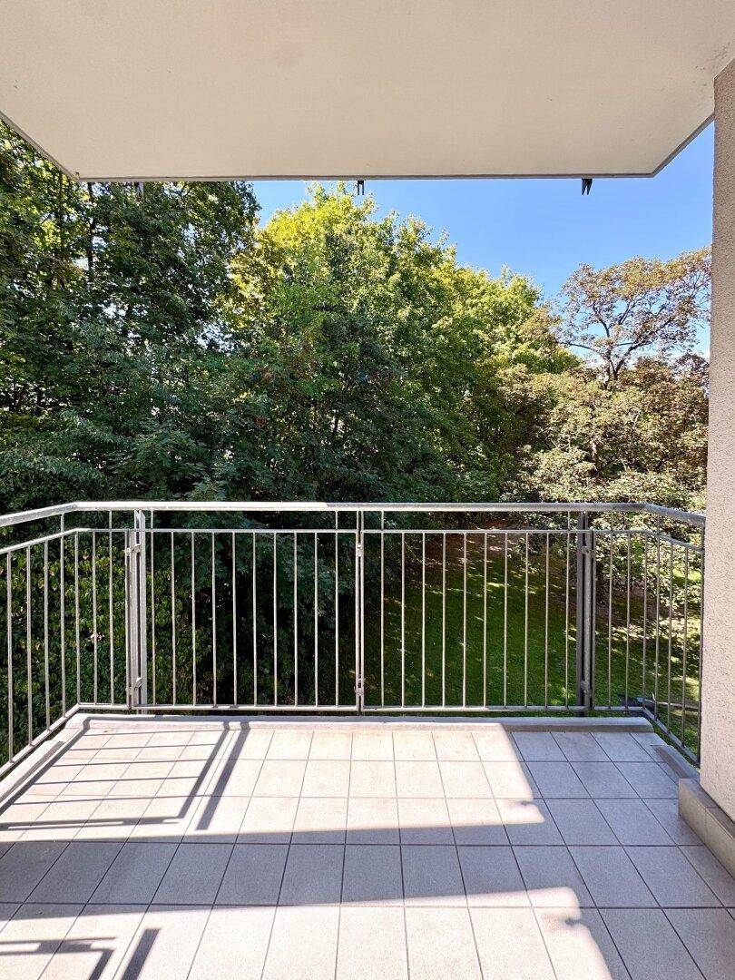 Sonniger Balkon mit Fliesenboden und weitem Blick in die grüne Natur.